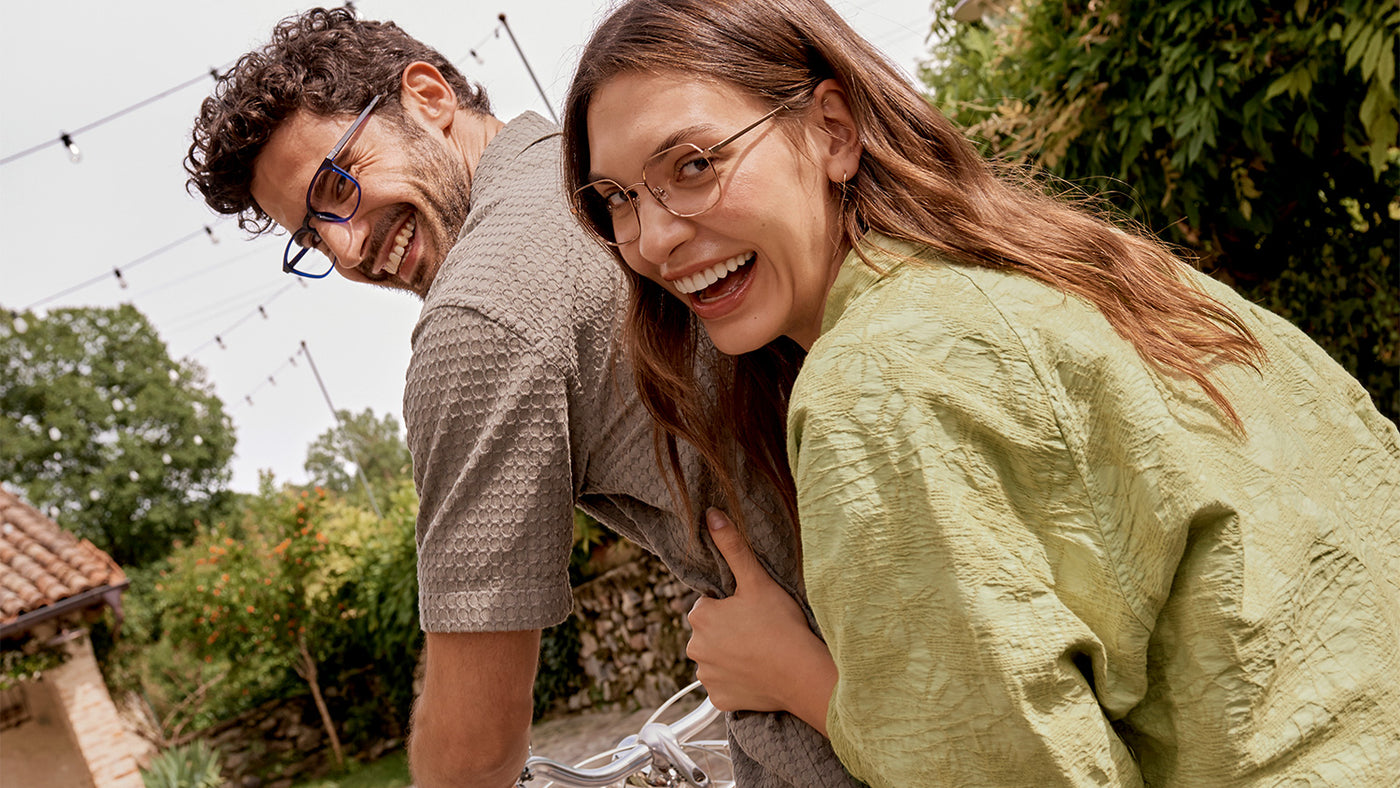 Man and Woman riding a bicycle in Italian landscape wearing sustainable eyewear