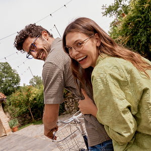 Man and Woman riding a bicycle in Italian landscape wearing sustainable eyewear